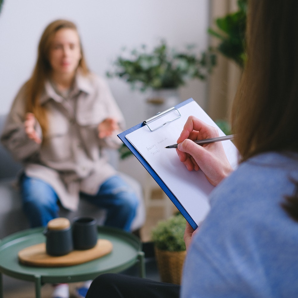 psychologist writing on clipboard during psychotherapy session